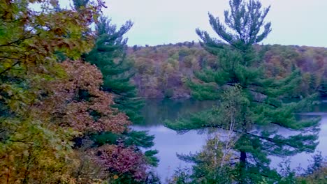 Bewegender-Zeitraffer-über-Einem-See-Mit-Bäumen-Am-Späten-Abend-Auf-Einem-Aussichtspunkt-Mit-Herbstlichem-Wald-In-Quebec