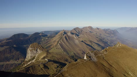 Overflying-mountain-cliff-and-revealing-landscape-below-Rochers-de-Naye-area,-Prealps---Switzerland