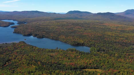 Un-Dron-Aéreo-Se-Inclinó-Hacia-Abajo-Sobre-Un-Sereno-Lago-Azul-De-Montaña-En-El-Bosque-A-Lo-Largo-De-Una-Cordillera-Cuando-Termina-El-Verano-Y-La-Temporada-Cambia-Para-Caer-En-Maine