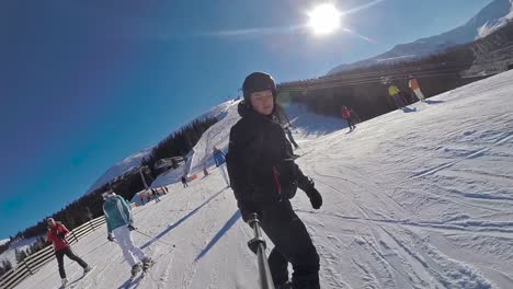 Front-selfie-stick-view-of-a-snowboarder-going-down-in-slow-motion-and-people-around
