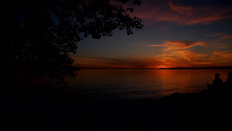 Time-lapse-of-an-Orange-Sunset-amongst-the-Silhouette-of-a-Tree,-at-Britannia-Beach,-Ottawa