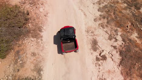 Close-tracking-shot-looking-down-on-a-four-wheeler-dune-buggy-driving-fast-on-a-dirt-road