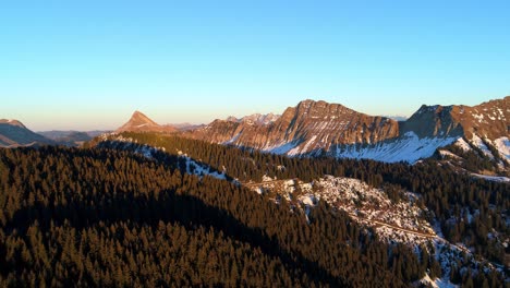 Abendlicht-über-Bergen-Mit-Teilweisen-Schneeflecken,-Die-Kiefernwald-überfliegen,-Herbstfarben