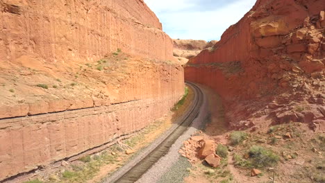 Flying-Down-Over-Train-Tracks-Cutting-Through-a-Desert-Canyon-in-Moab,-Utah