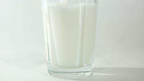 Milch-Wird-In-Ein-Glas-Gegossen,-Wobei-Die-Untere-Hälfte-Des-Glases-Aus-Der-Nähe-Zu-Sehen-Ist,-Mit-Einem-Hellen-Und-Klaren-Hintergrund