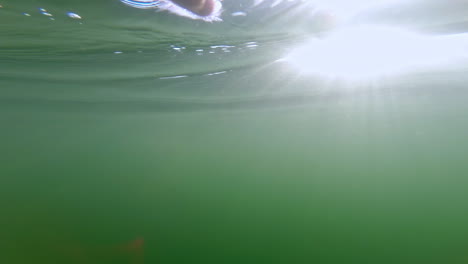 POV-Shot,-Male-swimmimng-underwater-with-air-bubbles-and-light-rays,-slowmotion
