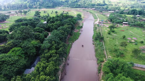 Aerial-shot-of-Elephants-standing-in-the-river-with-fields-on-each-side