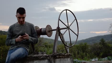 Young-man-texts-on-his-cell-phone-in-a-rural-setting