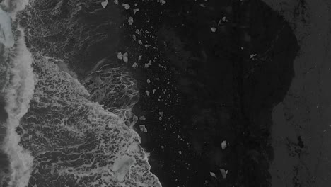 Slow-Motion-Aerial-Shot-Directly-Above-Crashing-Waves-on-Black-Sand-Beach