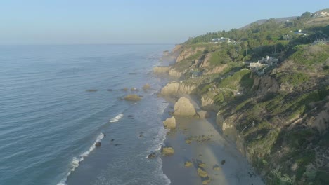Aerial-shots-of-El-Matador-beach-over-breaking-waves-and-rocks-on-a-hazy-summer-morning-in-Malibu,-California