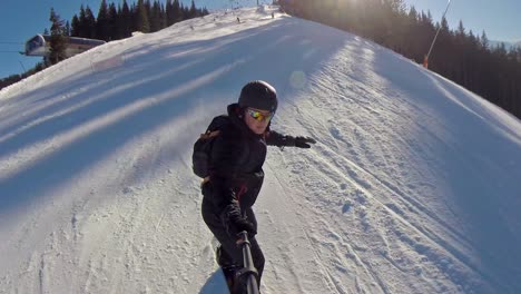 Vista-Frontal-De-Un-Snowboarder-Bajando-A-Través-De-Personas-Con-Un-Palo-Selfie-En-Un-Día-Despejado