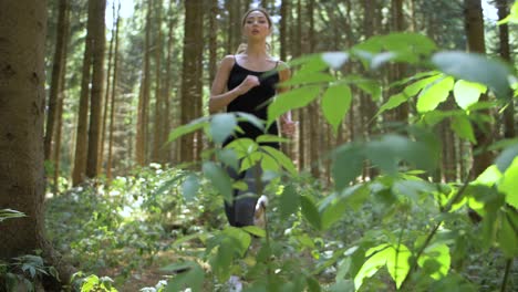 Tall,-thin-woman-running-through-wooded-area-as-she-is-exercising