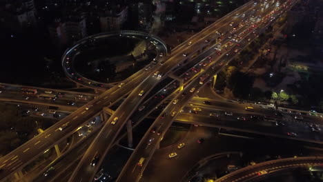 Aerial-shot-of-a-multi-layer-express-road-junction-at-night-with-heavy-traffic