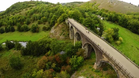 Aerial-view-cyclists-and-hikers-crossing-Headstone-Viaduct,-bridge-in-the-Derbyshire-Peak-District-National-Park,-Bakewell,-commonly-used-by-cyclists,-hikers,-popular-with-tourists-and-holiday-makers