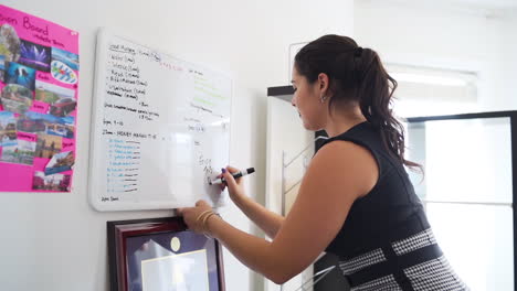 Young-business-woman-writing-on-a-white-board-in-her-office