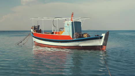Traditional-carvel-built-Greek-fishing-boat-moored-at-sea-RAMPED-SLOW-MO,-pan-up