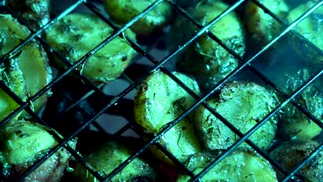 Camera-panning-across-closeup-of-browned-herbed-new-potatoes-in-a-wire-basket-on-a-hot-grill-with-red-embers-glowing-beneath