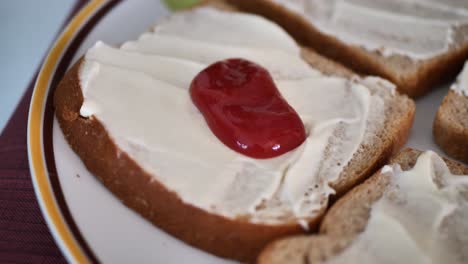 Squirting-ketchup-on-whole-wheat-bread-with-vegan-mayo-on-it