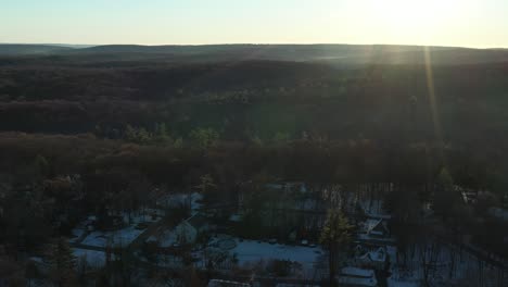 Drohnenflug-über-Häuser-In-Einem-Wald-Bei-Kaltem-Sonnenaufgang