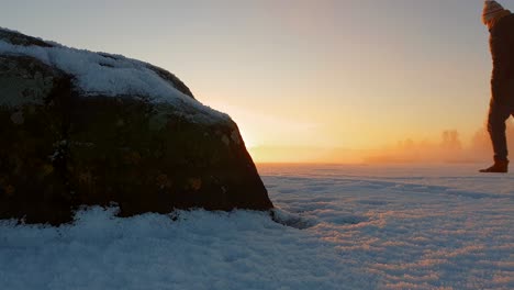 Alleinstehender-Mann,-Der-Bei-Goldenem-Sonnenuntergang-Auf-Gefrorenem-Eis-Spaziert,-Verschneiter-Winter-In-Arktischer-Landschaft