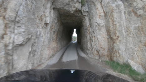 Driving-through-a-narrow-rock-tunnel-on-Needles-highway-in-Custer-State-Park,-South-Dakota