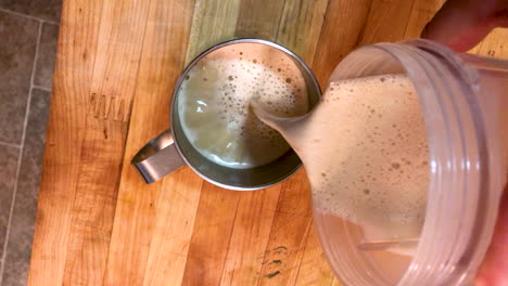 Bulletproof-ketogenic-coffee-with-butter-is-being-poured-from-a-blender-to-a-stainless-steel-cup