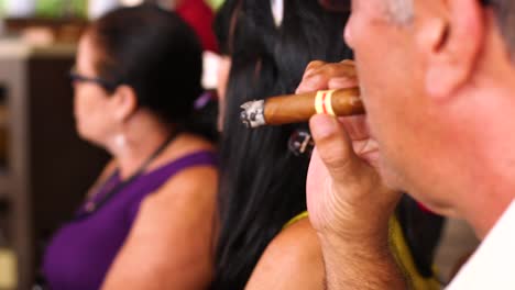 Caribbean-male-carefully-examining-and-smoking-a-cigar-with-friends