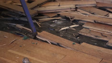 Close-Up-Shot-of-a-Blue-Collar-Worker-Using-a-Pry-Bar-to-Remove-Water-Damaged-Wood-Flooring