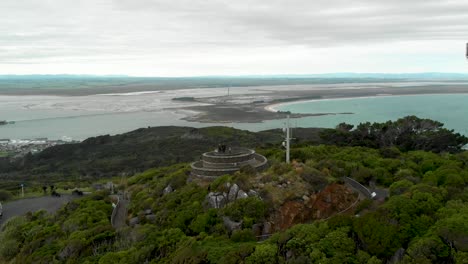 Couple-at-Bluff-Hill-Lookout-with-ocean-and-landscape-in-the-background-on-cloudy-day---New-Zealand---Aerial-Drone