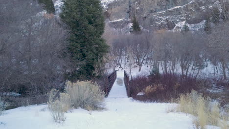Point-of-view-walking-towards-a-bridge-on-a-snow-covered-path-in-the-wilderness