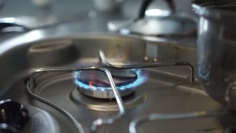 Close-up---Lighting-up-gas-stove-burner-fire-and-a-pot-of-water-in-kitchen-of-motorhome