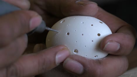 Closeup-of-a-person-carving-chicken-egg-using-a-drill-with-bare-hands