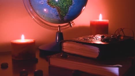 Globus-Mit-Flackernden-Kerzen,-Hellem-Hintergrund-Auf-Einer-Holzoberfläche-Mit-Steinen-Und-Alten-Büchern