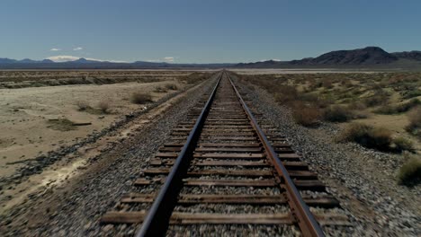 Fast,-overhead,-pull-back-aerial-view-of-straight-railroad-tracks-in-the-desert