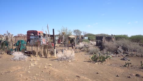 Wide-of-Namibian-Campsite-with-Old-Truck,-Fences-and-Dry-land-with-Trees-against-a-Blue-Sky