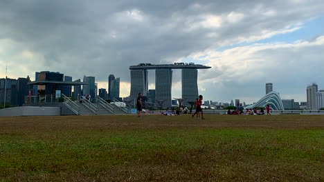 A-footage-shot-of-a-boy-running-after-a-ball-in-an-open-field-with-Marina-Bay-Sand-Hotel-Singapore-in-the-backgound