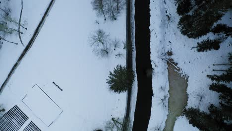 Flying-over-small-river-during-winter-in-small-village