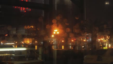 Bokeh-City-Lights-Coming-into-Focus-through-a-Rainy-Window-at-Night-Time