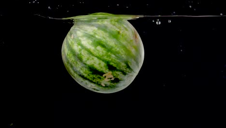 Colorful-and-vibrant-watermelon-being-dropped-into-water-in-slow-motion