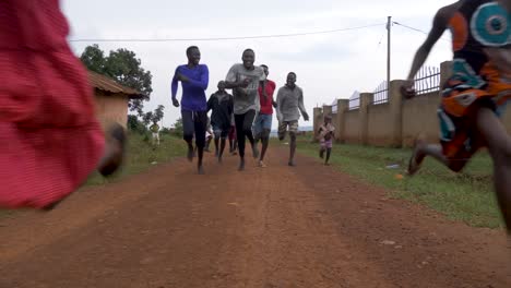 Eine-Gruppe-Afrikanischer-Jugendlicher-Und-Kinder-Rennt-In-Zeitlupe-Mit-Einem-Lächeln-Im-Gesicht-Eine-Unbefestigte-Straße-Entlang