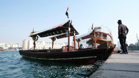 Traditionelles,-Ikonisches-Abra-Boot-Im-Berühmten-Dubai-Creek-Mit-Indischen-Touristen,-Die-Die-Aussicht-In-4K-Auflösung-Genießen