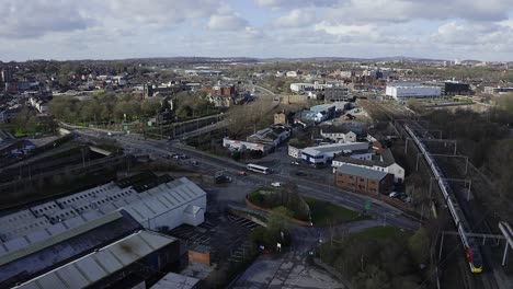 Aerial-footage-of-trains-approaching-Stoke-on-Trent-train-station-in-the-midlands-by-the-canal,-waterside-and-A50-motorway,-the-midway-point-for-commuters-who-travel-north-and-south-through-the-UK