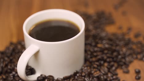 Schwenk-Einer-Kaffeetasse,-Umgeben-Von-Kaffeebohnen