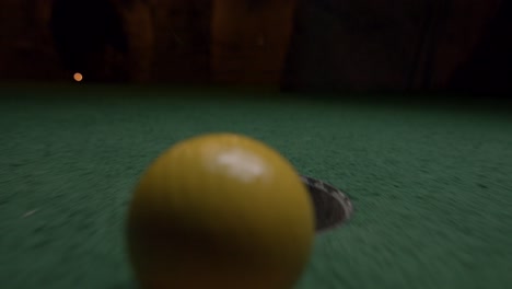 A-yellow-mini-golf-ball-falls-into-the-golf-hole-and-bounces-in-the-pocket-on-a-course