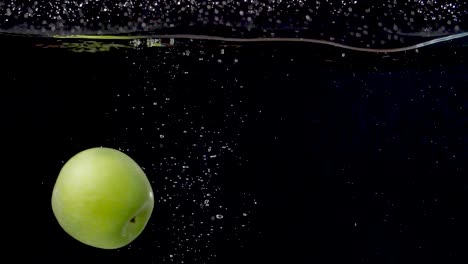 Vibrant-green-apple-being-dropped-into-water-in-slow-motion