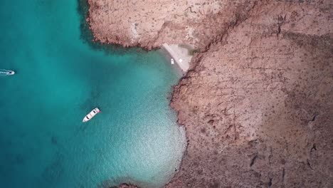 Aerial-cenital-plane-shot-of-a-little-beach-and-a-yacht-in-Partida-Island,-Archipielago-Espritu-Santo-National-Park,-Baja-California-Sur