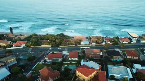 Aerial-view-taken-with-a-drone-flying-over-residential-homes-with-a-view-of-the-sea-in-the-distance