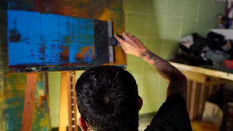 Chinese-man-painting-making-art-in-studio-with-dramatic-lighting