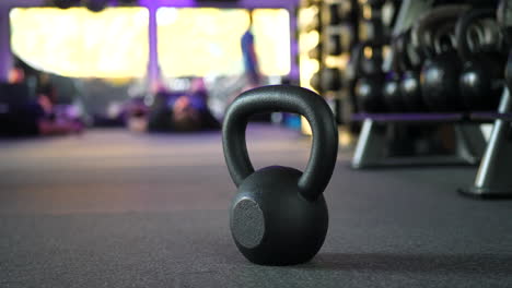 A-kettlebell-weight-in-a-gym-with-people-working-out-in-a-physical-fitness-training-class-in-the-background-SLIDE-LEFT