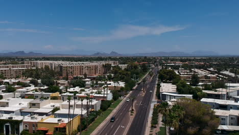 Drone-footage-over-residential-area-and-busy-road-in-Scottsdale,-Arizona-with-Camelback-Mountain-in-the-background